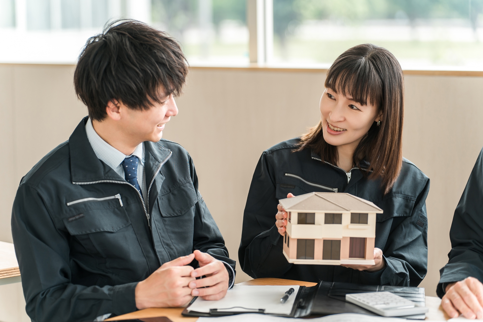 家の模型を持ち話す女性