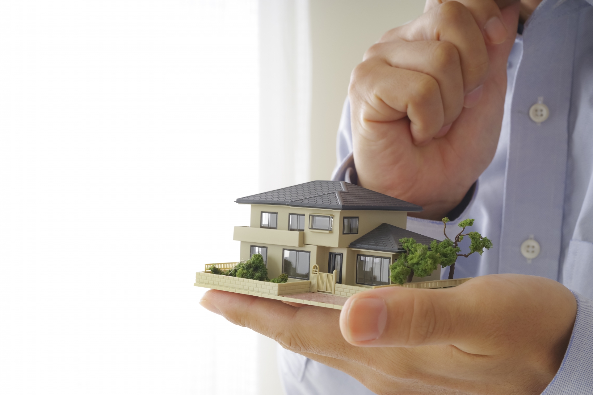 家の模型をもって考える男性