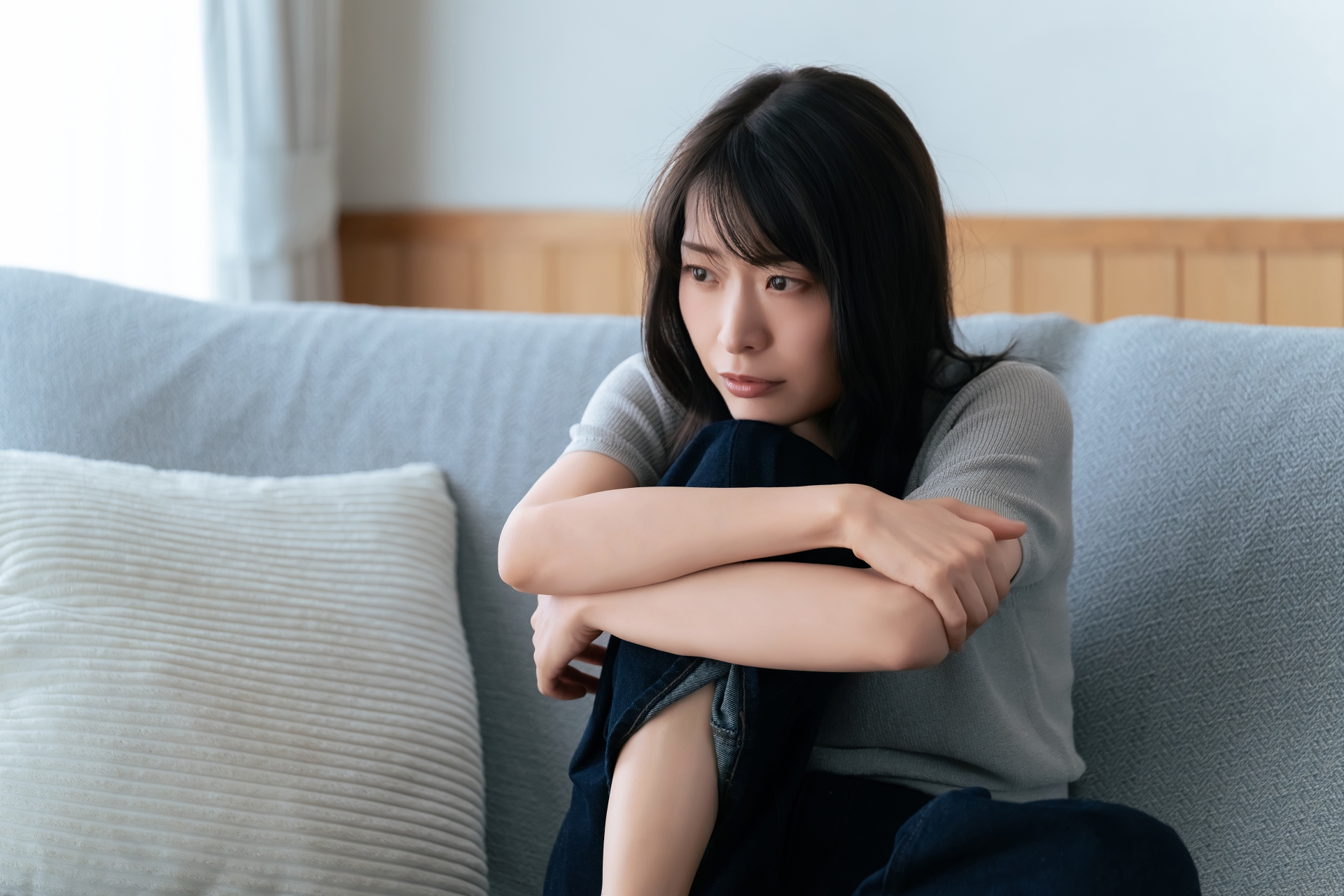 ソファで膝を抱える女性
