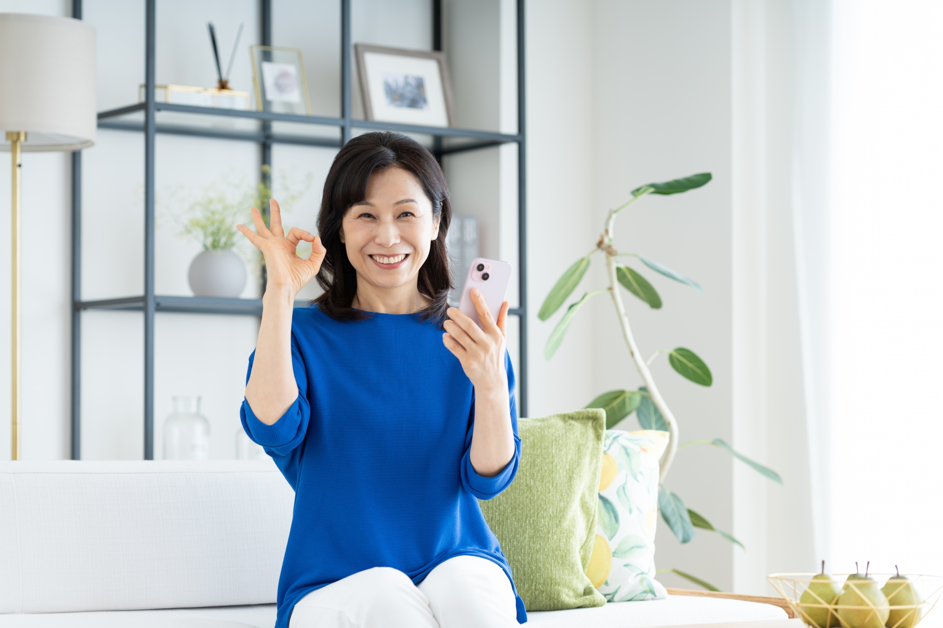 スマホでOKサインのミドルの女性