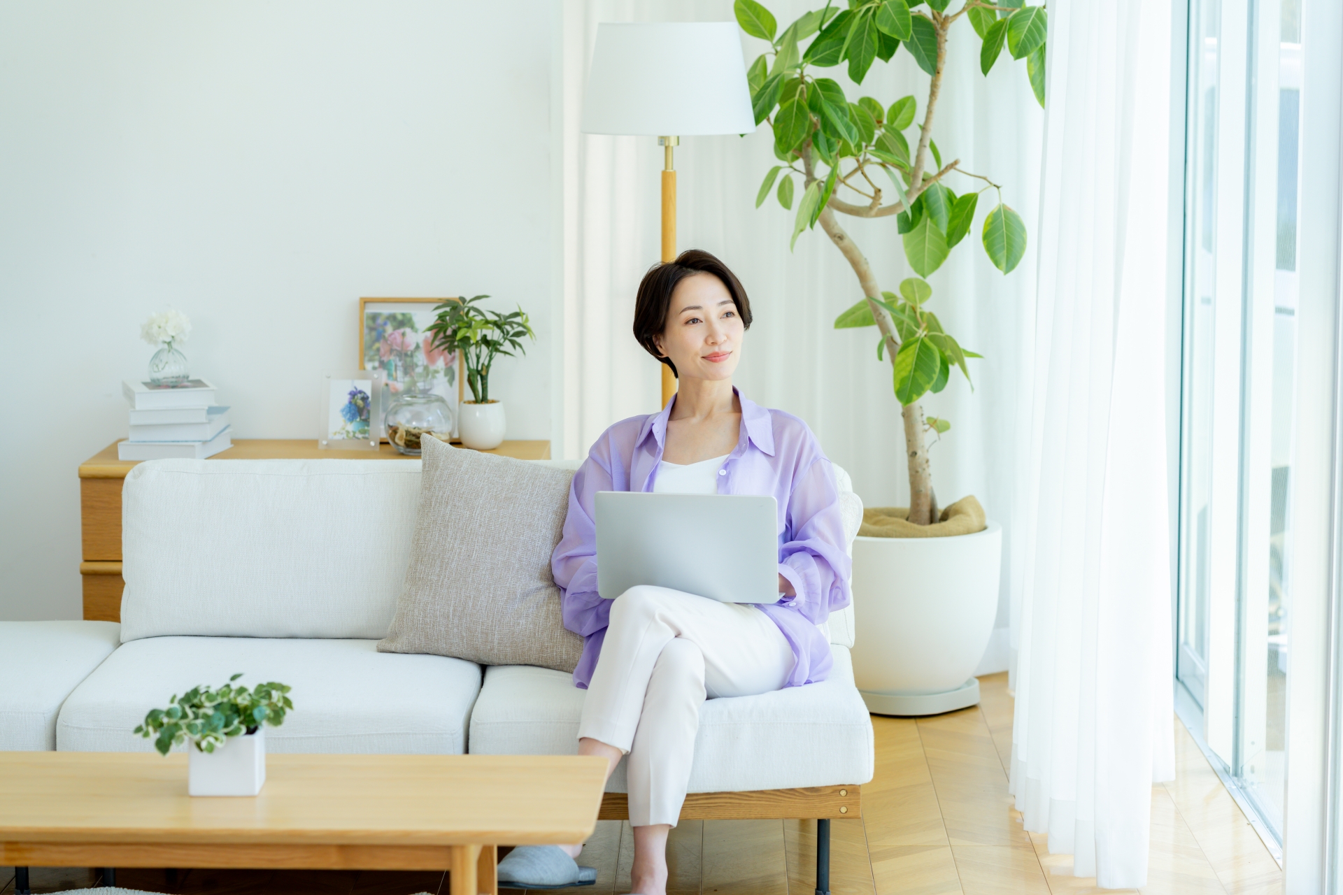 部屋でノートパソコンを使うミドル女性
