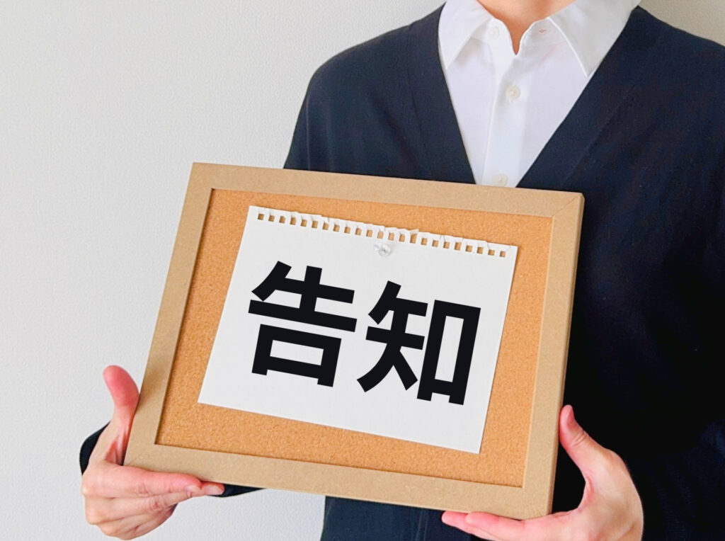 告知と書かれたカードを持つ人