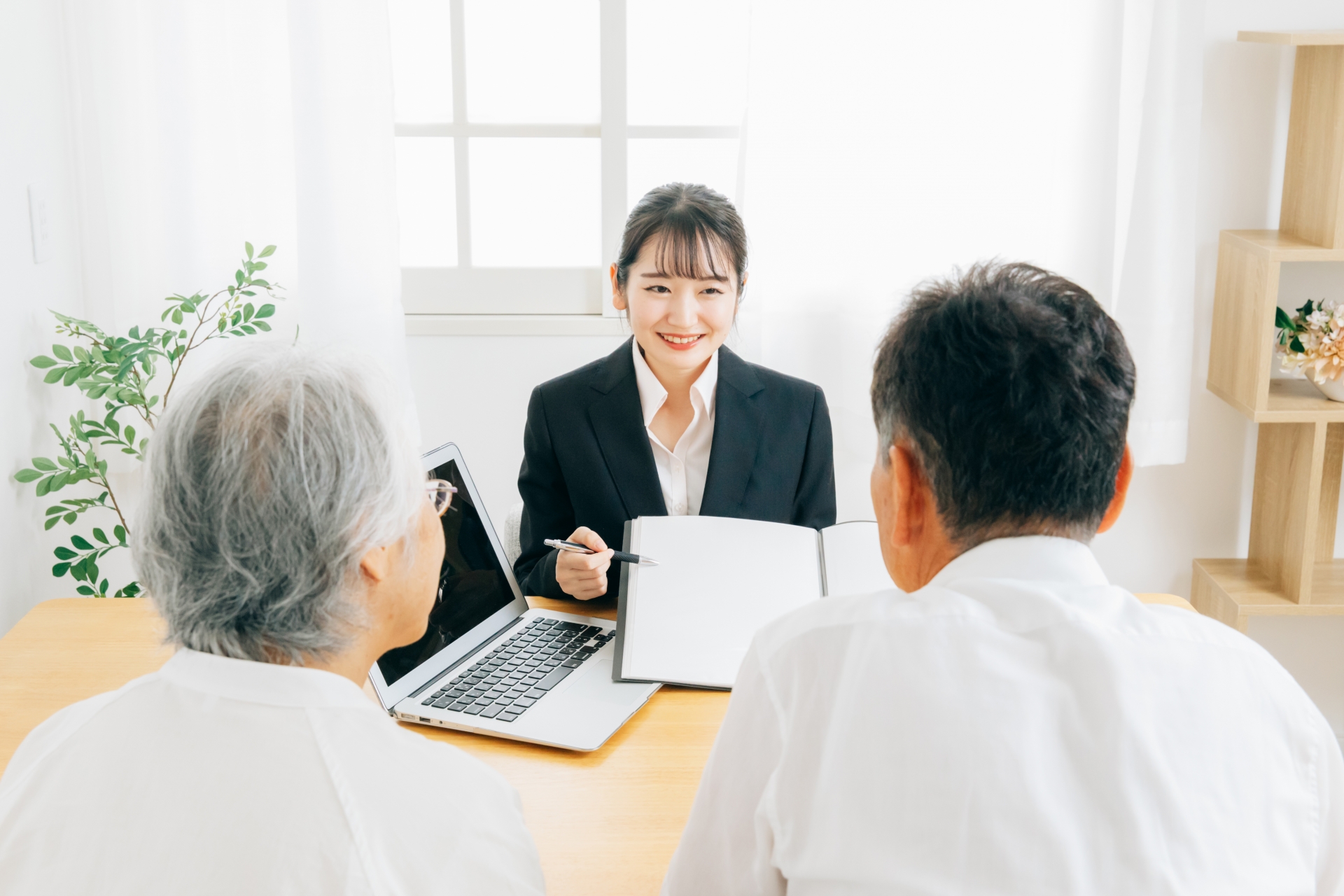 資料で説明するスーツ姿の女性と高齢者夫婦
